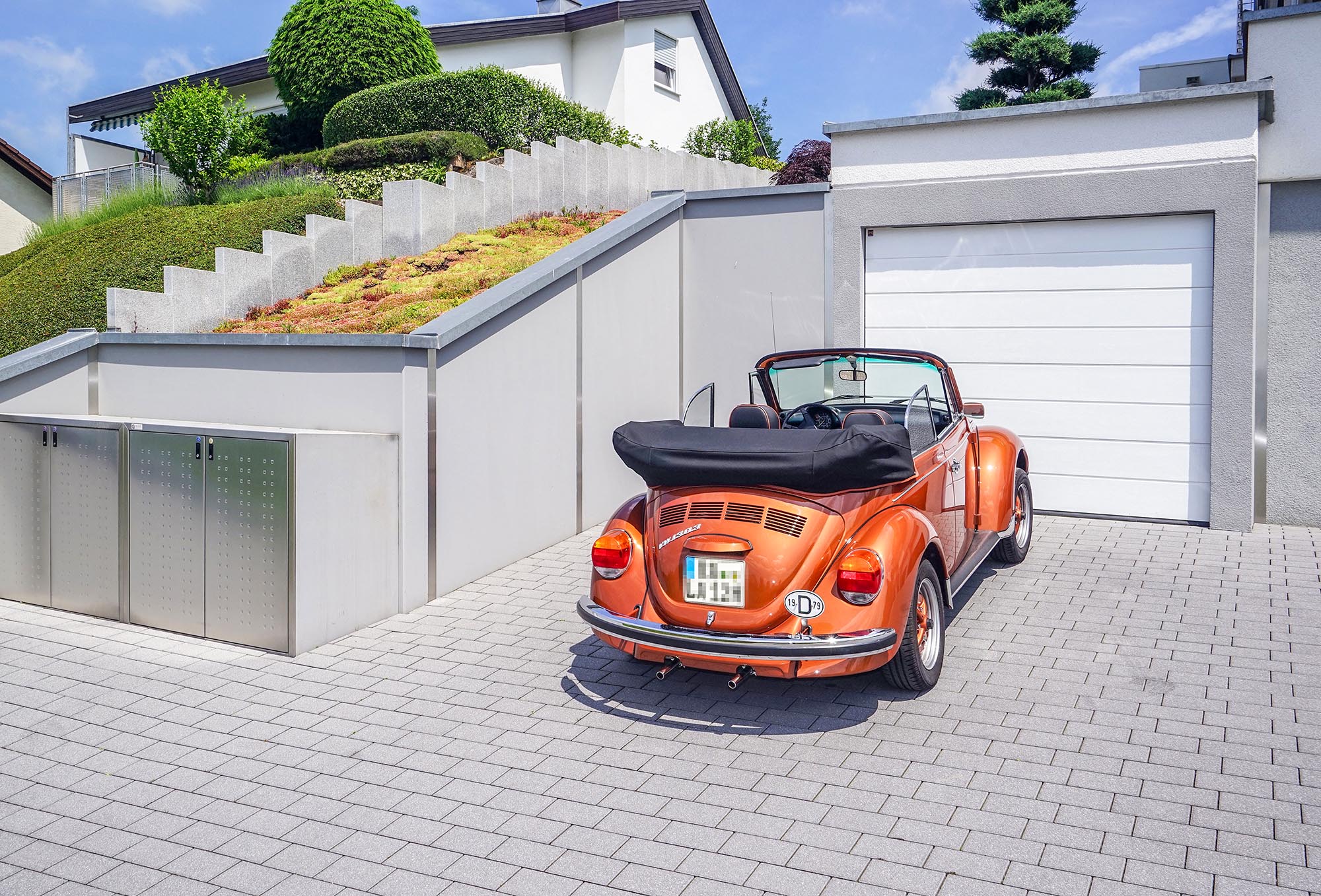 Ein gerendertes Bild, dass eine Hanggarage zeigt, vor der ein alter roter VW Käfer parkt.